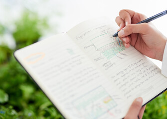 Obraz premium Scientist, hand and writing notes for plant research, innovation or medical analysis for botany. Science, notebook and closeup of person in lab with leaf for natural experiment info, test and exam