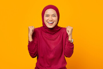 Excited Asian muslim woman celebrating victory smiling looking a
