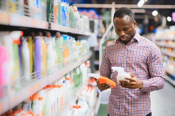 African man holding bottle of household chemicals in big store