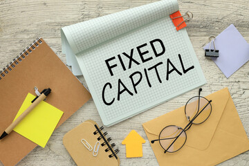 FIXED CAPITAL stationery and calculator on financial chart. text on notepad page with spiral