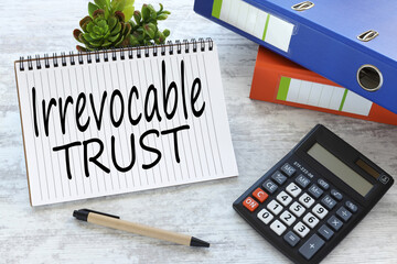 work desk with folders and notepad. text Irrevocable trust. the concept of trust