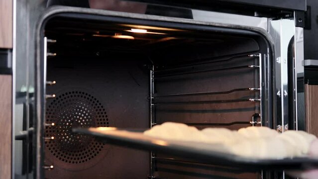 Woman-cook puting croissant for baking in the oven.