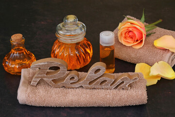 	Spa composition: aromatic oil, towels and the word Relax.