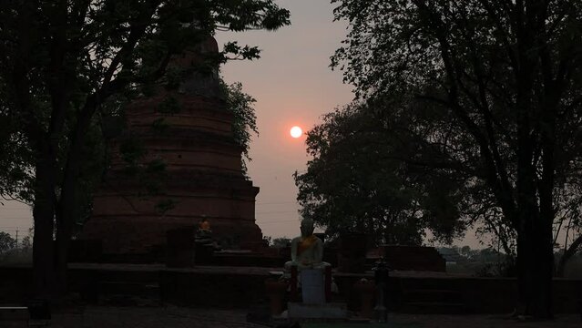 natural video background of the round sun rising from the horizon in the morning behind the old Buddha statue,Wat Yai Chai Mongkhon,is a beauty that happened spontaneously while traveling to Ayutthaya
