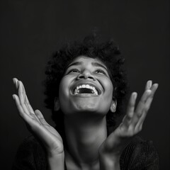 An overjoyed individual with uplifted hands and a beaming smile in a black and white portrait.