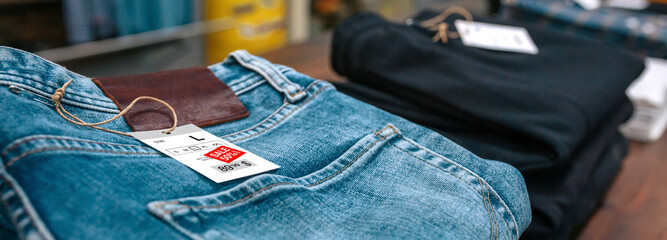 Close up of label with discount price over a blue jeans pants on vintage store. Sales season and...