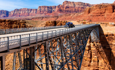 Famous arch bridge over Marble Canyon washed out by Colorado river called new “Navajo Bridge“. Tall majestic steel construction from 1995 next to its twin from 1929. Truck crossing it on Highway 89.