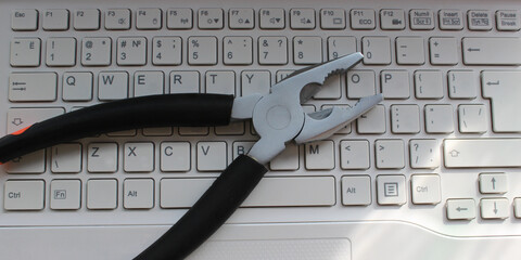Pliers on a white computer keyboard with latin characters only stock photo