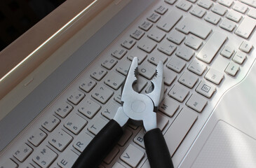 Computer Repairing Concept. Steel Pliers On Laptop Keyboard Angle View