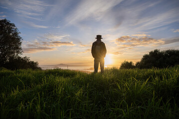 Man enjoying the sunrise at Mt Eden summit. Rangitoto Island in the distance. Auckland. - 787948701