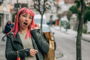 pink haired urban young woman with shopping bags on the street