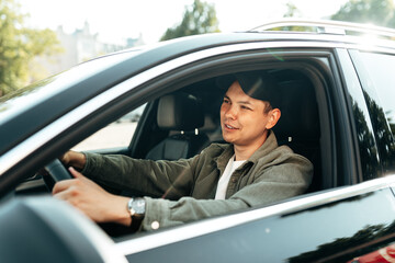 Young smiling man sitting in a car with open window - 787964364