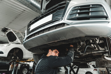 Auto mechanic repairs running gear of a car in car service - 787965366