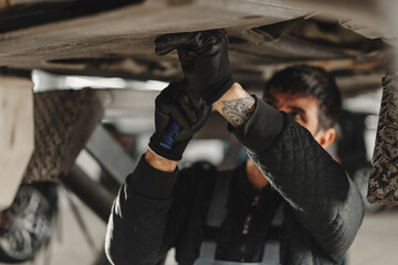 Workman mechanic working under car in auto repair shop - 787965932