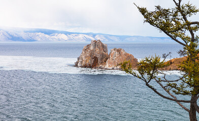 Baikal  Lake in May. Olkhon Island. Famous Shamanka Rock is natural landmark and place of attraction for tourists. Spring seascape with ice floes melting near Burkhan Cape. Natural seasonal background