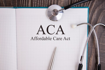 Notebook page with text ACA Affordable Care Act, on a table with a stethoscope and pen, medical...