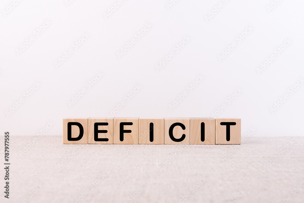 Fototapete deficit word concept written on wooden cubes blocks lying on a light table and light background
