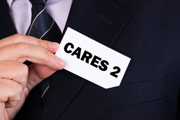 Businessman putting a card with text CARES 2 in the pocket. Business concept