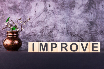 Word IMPROVE made with wood building blocks on a gray background