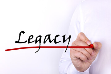 A person writes text, a word, the phrase Legacy with marker on a light background. Business concept.