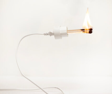 Conceptual electric cable and plug on fire against a white background