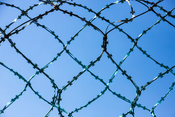 Stone wall with barbed wire against blue sky