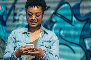 young african american woman with phone on graffiti wall