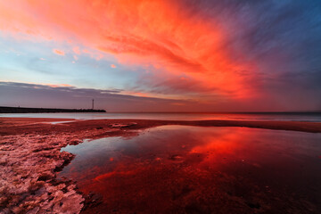 Dramatic red sunset over rocky coastline and entrance to port of Klaipeda, Lithuania