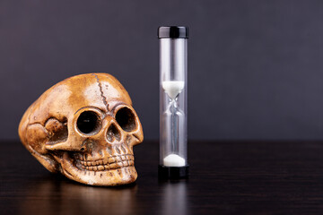 Skull of a dead man with an hourglass on a dark background. Concept, symbol of the transience of...