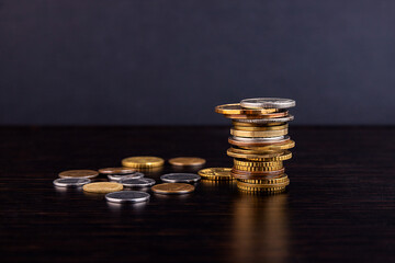 A tower of metal coins, euro, dollar, folded on a dark office desk. Business concept. Bank.