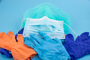 A pair of thin blue and orange medical latex gloves and a protective mask on a blue background....