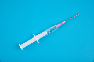 Disposable medical syringe with a needle on a blue background.