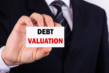 A businessman is holding a tablet with the text Debt Valuation in front of him in his hands. Business concept