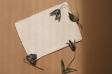 Overhead view of a blank piece of homemade deckle edge card with flowers on a wooden table