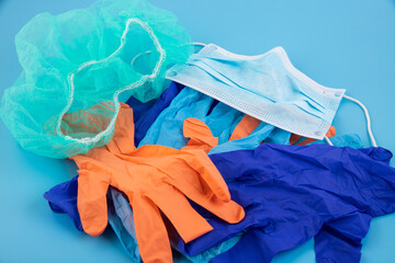 A pair of thin blue and orange medical latex gloves and a protective mask on a blue background....