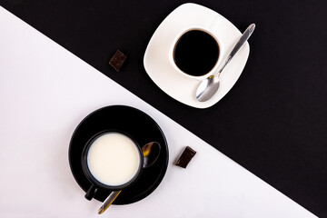 A black cup and saucer on a white background and a white cup and saucer on a black background. The...