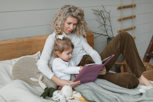 Mother and daughter sitting in bed reading a book