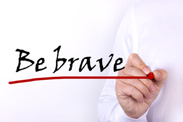A person writes text, a word, the phrase Be Brave with marker on a light background. Business...