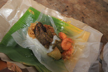 Nasi Bungkus, a typical Indonesian food served with oil paper filled with rice, fresh vegetables,...