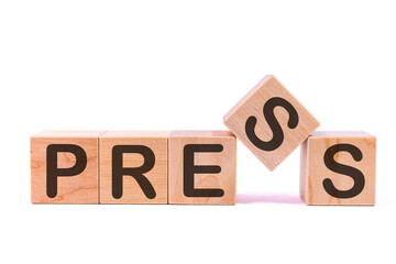 Word PRESS is made of wooden building blocks lying on the table and on a light background. Concept.