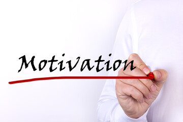 A person writes text, a word, the phrase Motivation with marker on a light background. Business...