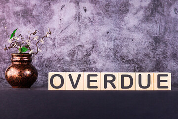 Word OVERDUE made with wood building blocks on a gray background