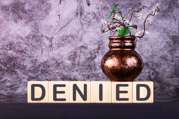 Word DENIED made with wood building blocks on a gray back ground