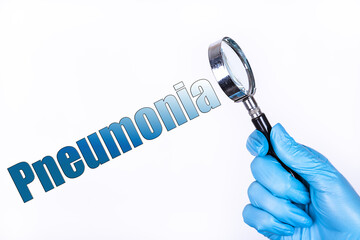 PNEUMONIA text written on the background of a magnifying glass in the doctor hand in a medical...