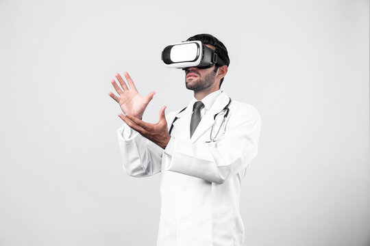 Smart doctor looking VR glass and standing with white background. Caucasian doctor holding and checking medical data while wearing virtual reality world or metaworld. Innovation technology. Deviation.