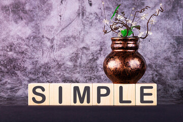 Word SIMPLE made with wood building blocks on a gray background