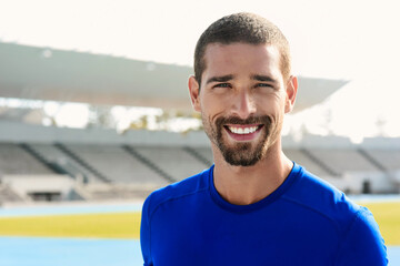 Portrait, happy man and runner at stadium for sport, wellness or exercise for body health in Australia. Face, smile and athlete at race track for fitness, workout or young person training outdoor