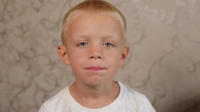 A close-up of an emotional boy shows his fallen baby tooth, he moves his tongue and shows a hole between his teeth.