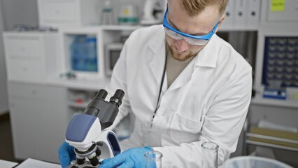 Bearded man analyzing sample in laboratory microscope clinic science research