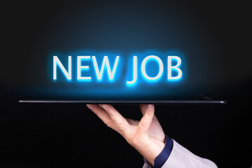 Man hand holds a tablet over which a neon text is written, the word NEW JOB. Business concept.